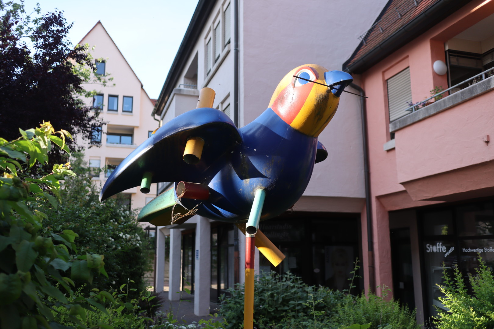 a large, colourful plastic sparrow, mounted on a plinth